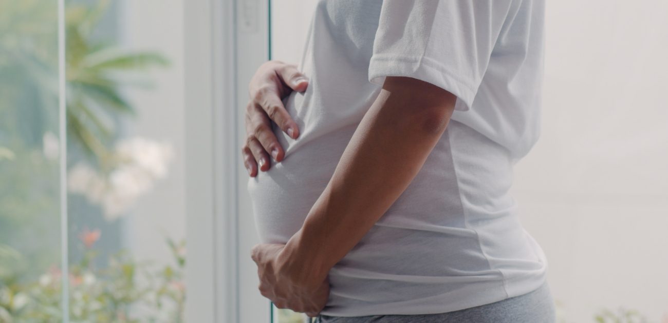 امرأة حامل تحتضن بطنها بيديها