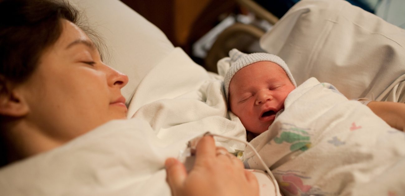 امرأة تنظر إلى طفلها المولود حديثًا بجانبها