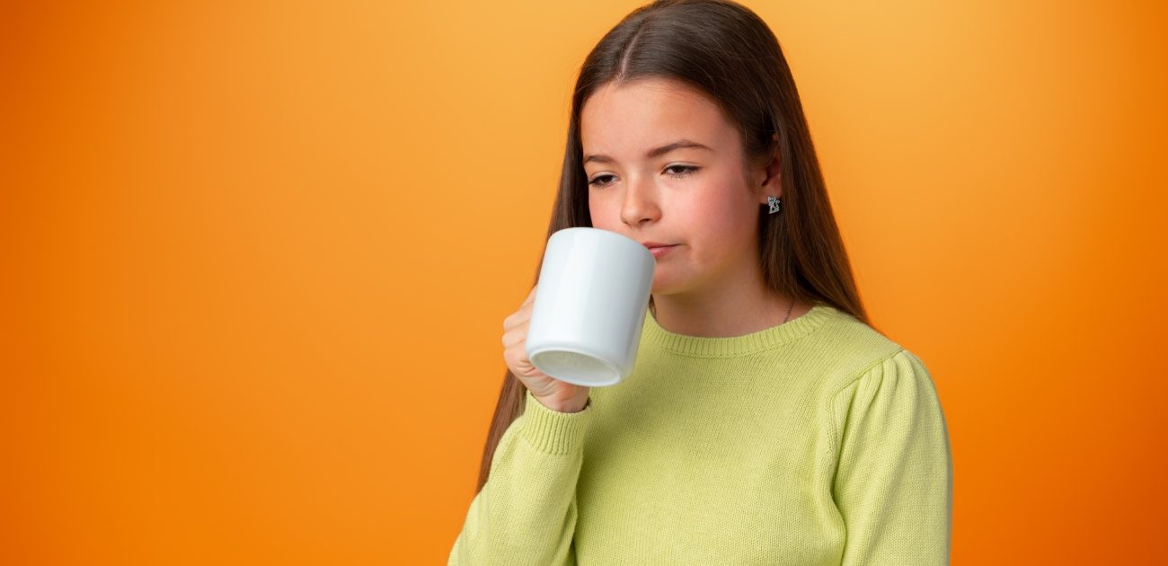طفلة مُتعَبة تُمسك كوبًا من الشاي