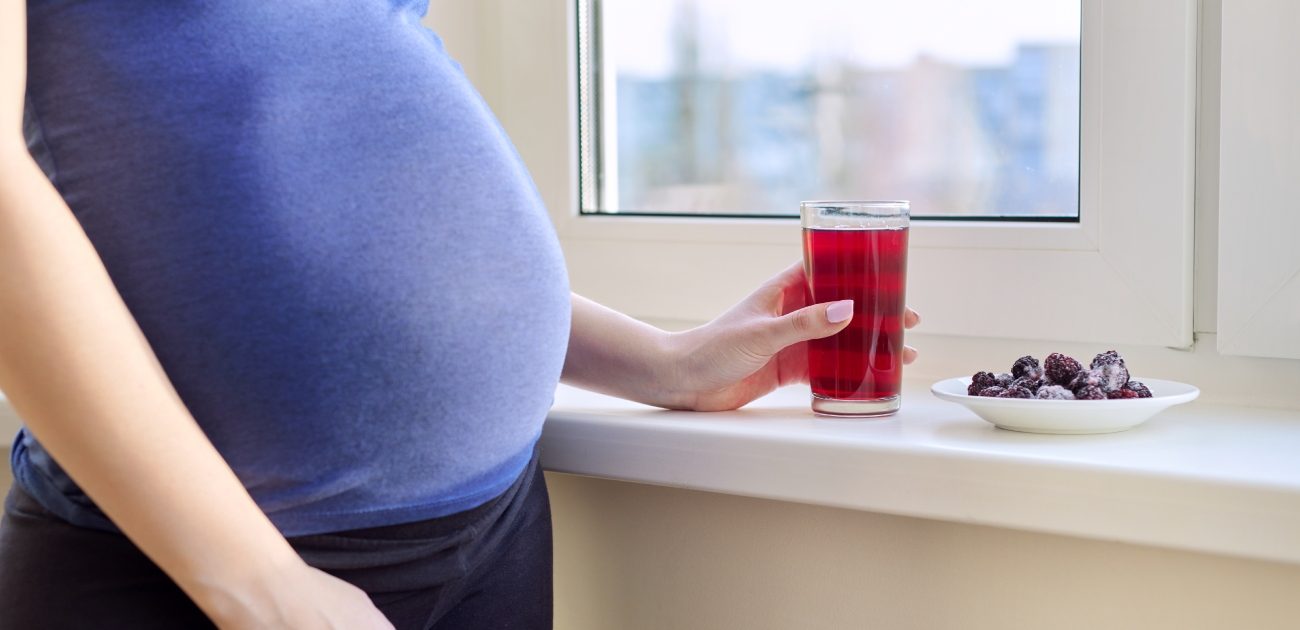 بطن امرأة حامل مع كوب من العصير