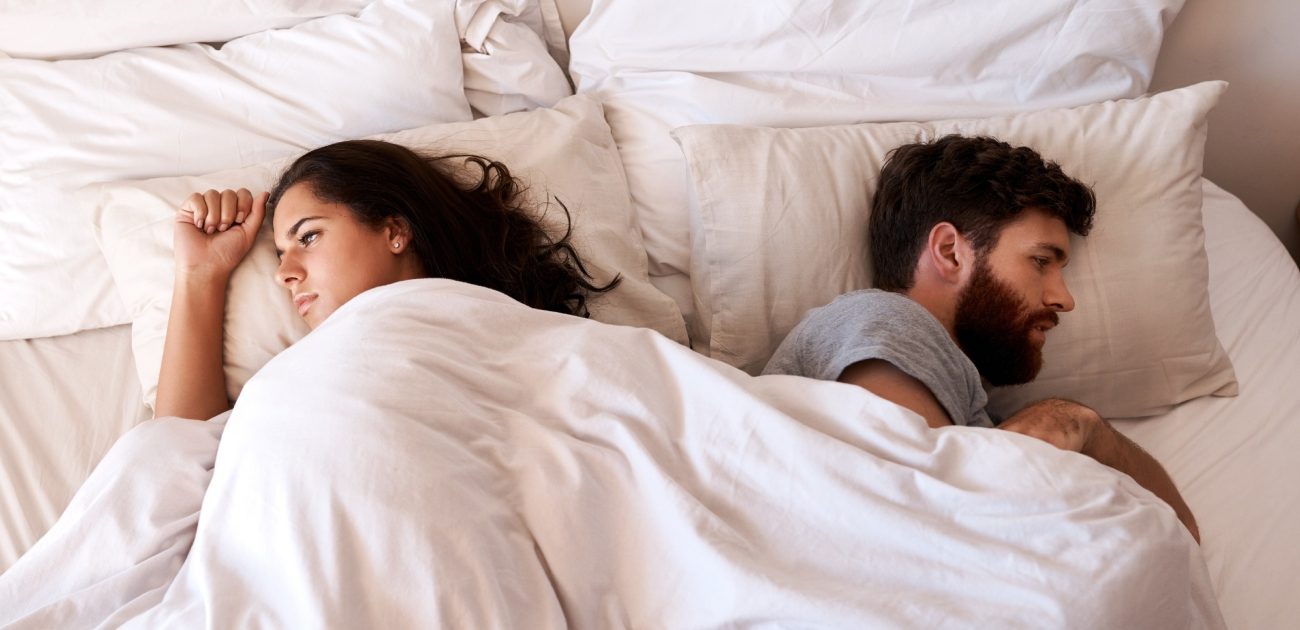 زوجان متخاصمان ينامان عكس بعضهما على السرير