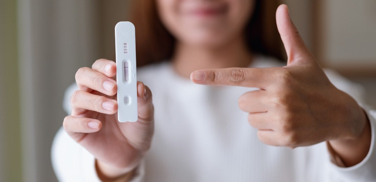 امرأة مبتسمة تُمسك اختبار الحمل وتُشير إليه بإصبعها
