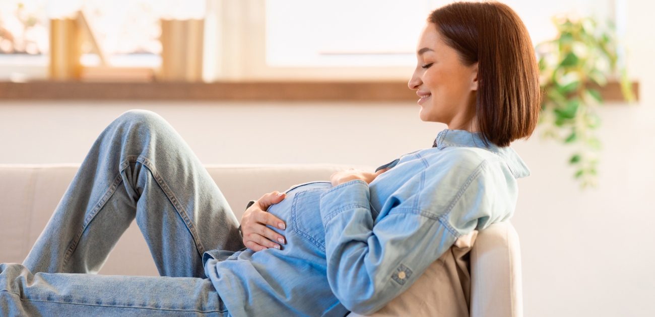 امرأة حامل مبتسمة مستلقية على الأريكة