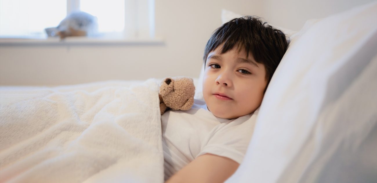 طفل مستلقٍ في سريره ومعه دمية