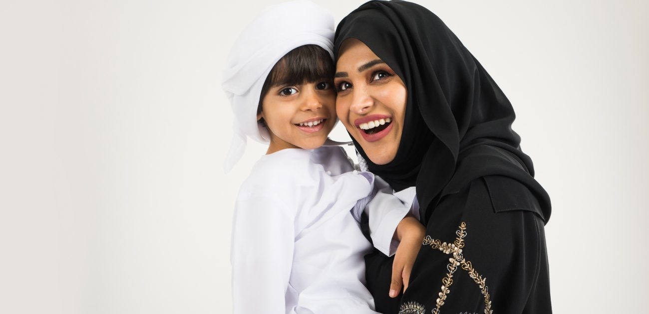 أمّ عربيّة تحمل طفلها وهما يضحكان