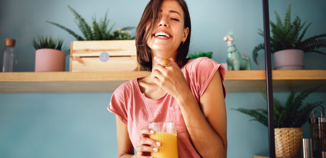 امرأة تضحك وتمسك كوب من العصير