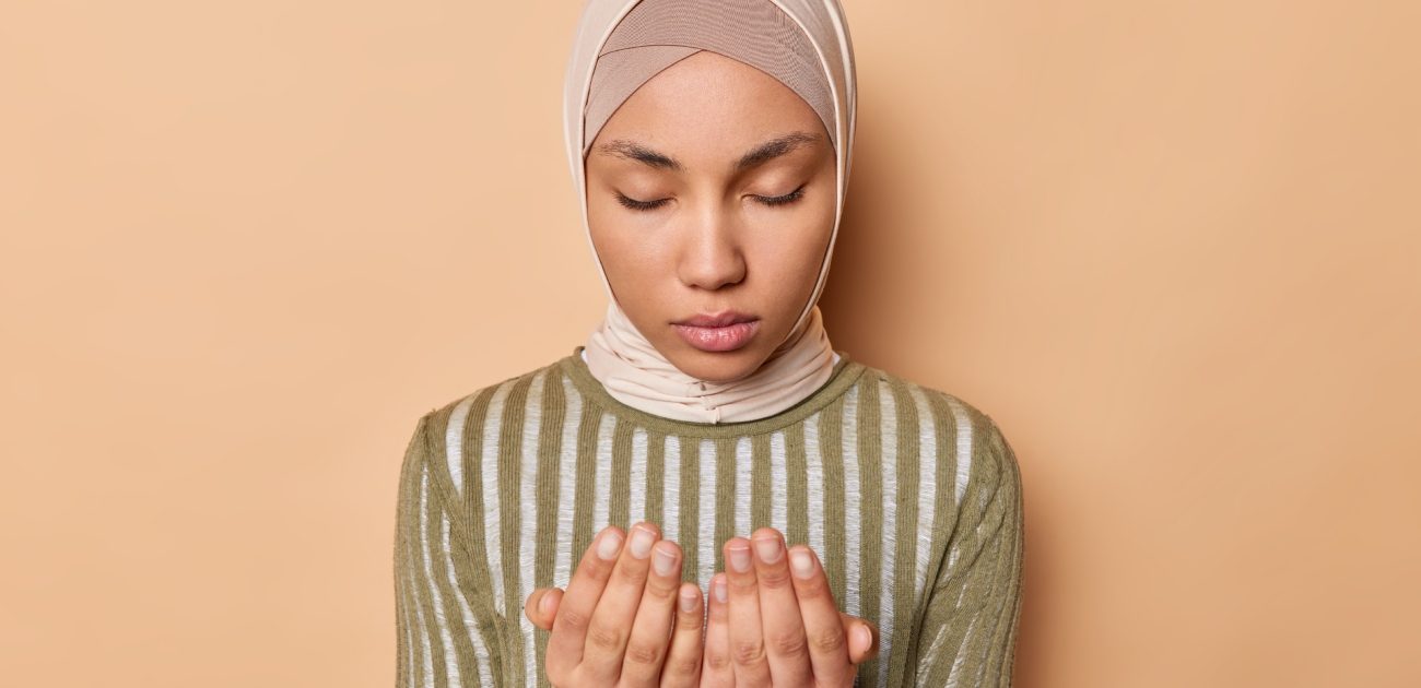 امرأة مسلمة ترفع يديها للدعاء