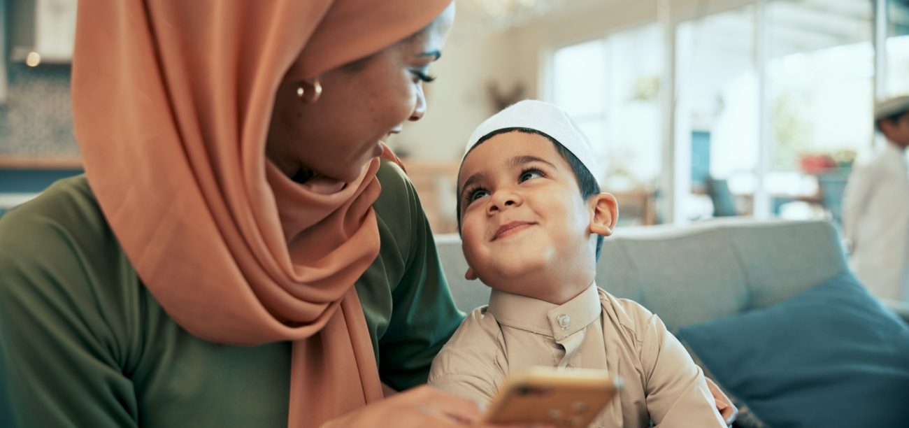 امرأة عربيّة تمسك هاتفها وتنظر إلى طفلها الذي ينظر إليها