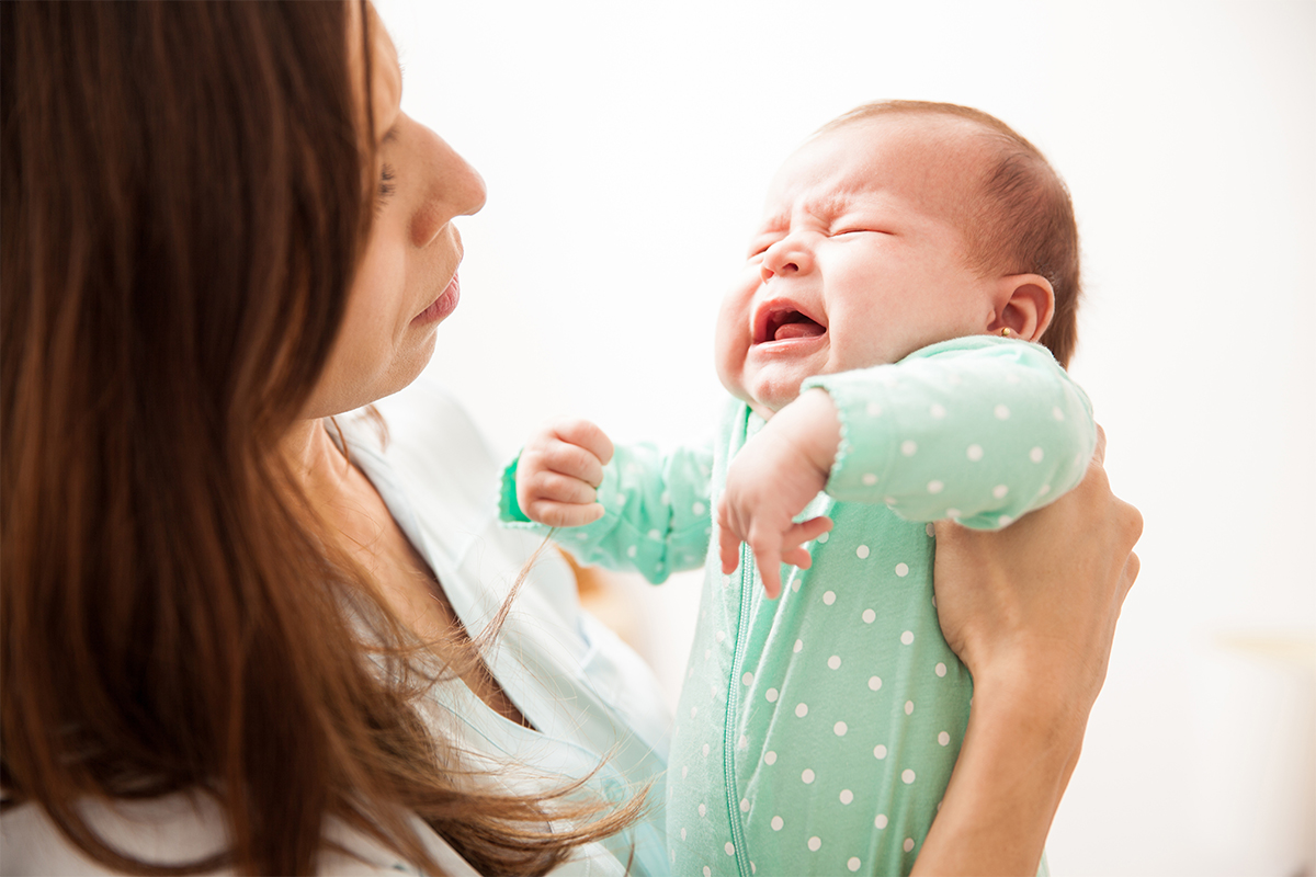 أم تحاول تهدئة طفلتها الرضيعة