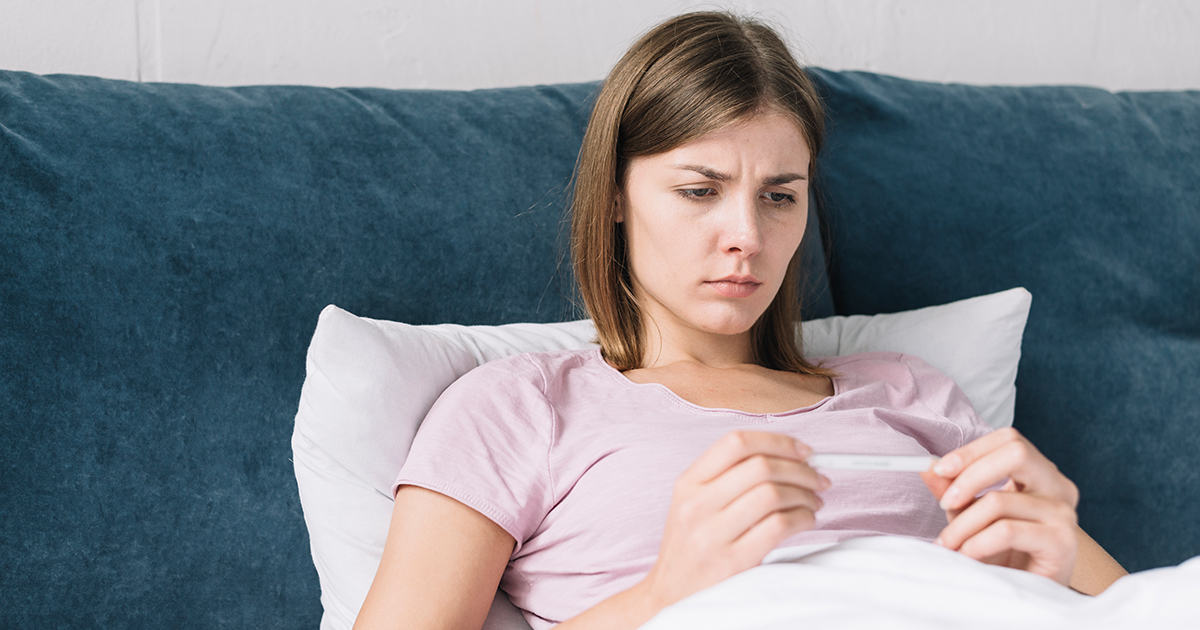 إمرأة في الفراش تشاهد نتيجة اختبار الحمل المنزلي
