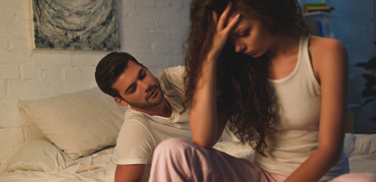 امرأة حزينة تجلس مع شريكها على السرير