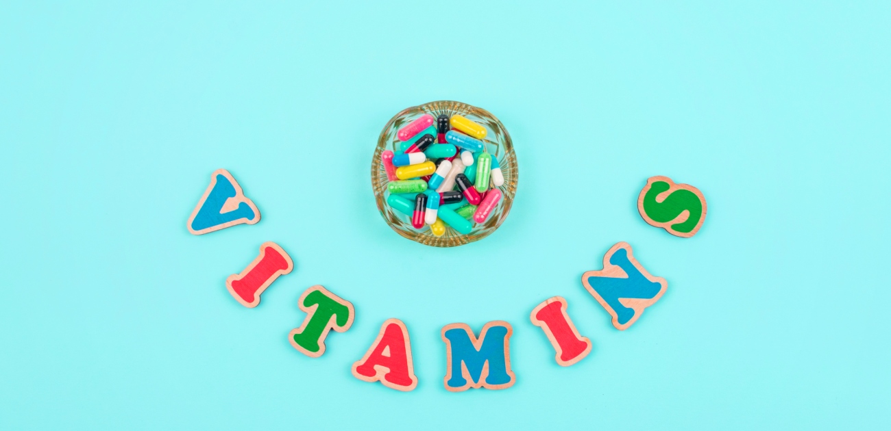 حبوب من الفيتامينات في علبة دائريّة وكلمة "Vitamins" أسفلها