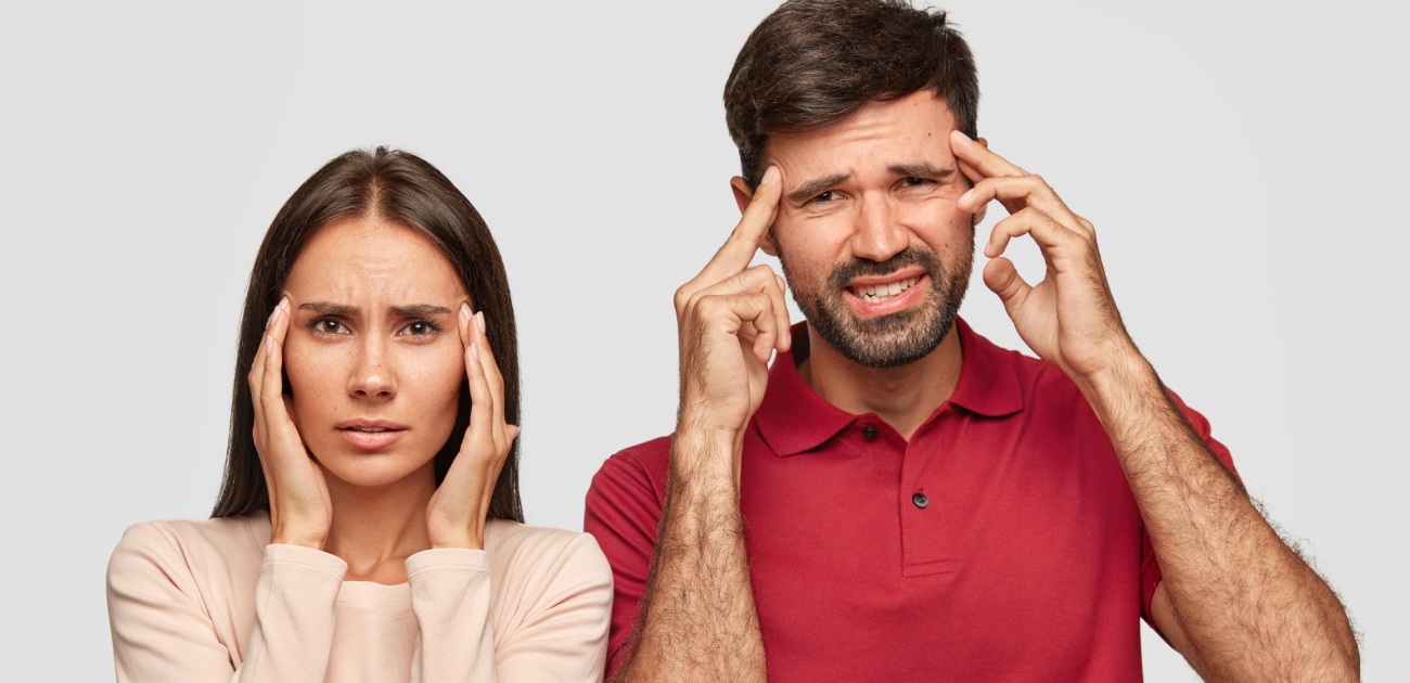 زوجان يضع كلّ منهما يديه على رأسه وكأنّهما يُعانيان من مشكلة أو ألم
