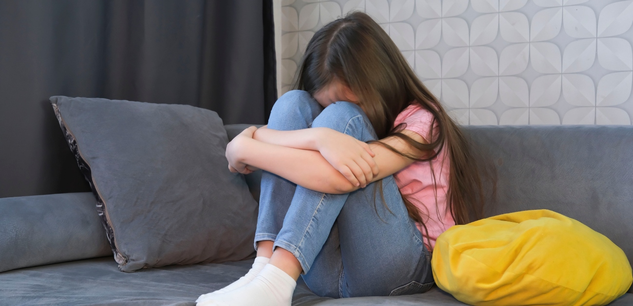 طفلة حزينة تجلس على كنبة