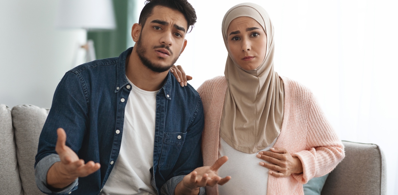 امرأة حامل مع زوجها يجلسان متفاجآن