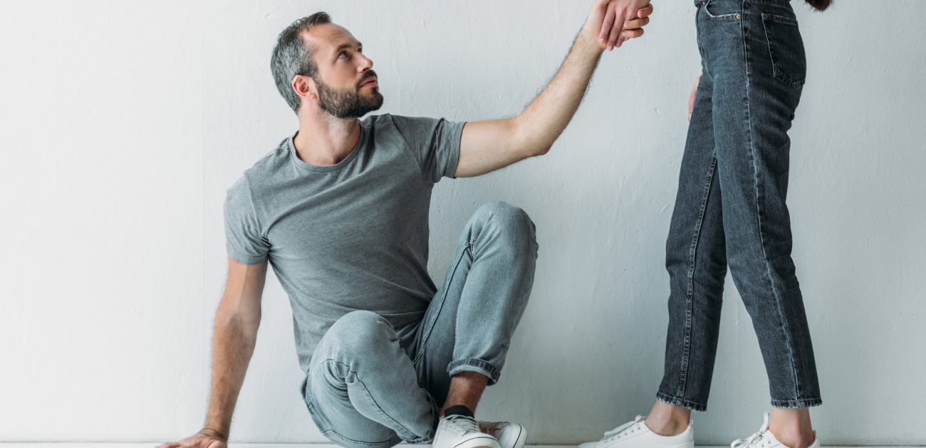 رجل يجلس على الأرض ويمسك يد امرأة تقف بجانبه