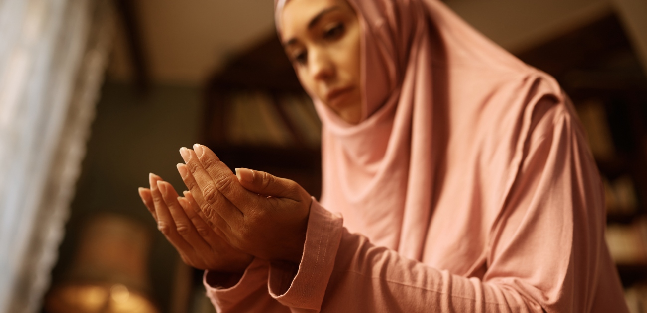 امرأة ترتدي ملابس الصلاة وتدعو اللهِ