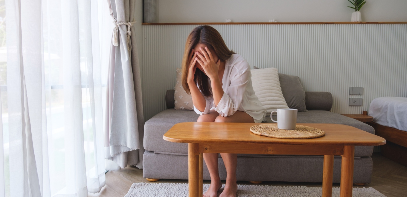 امرأة حزينة تضع يديها على رأسها تجلس على الكنبة وحدها