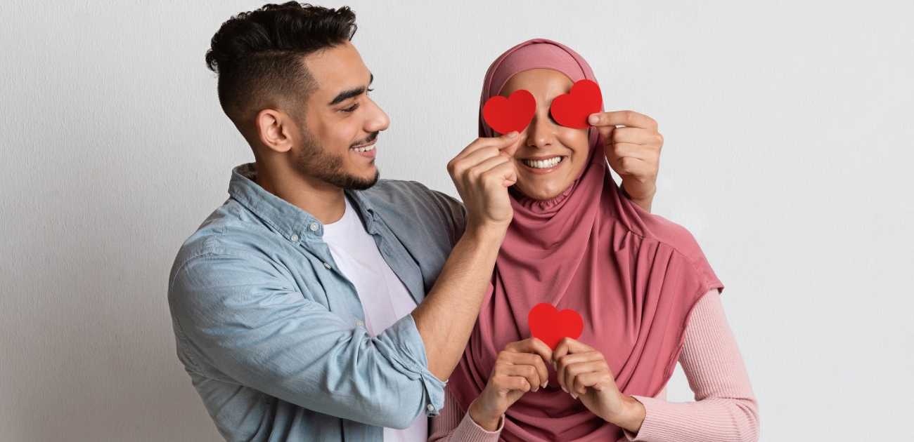 رجل يضع قلوبًا حمراء على عيني زوجته