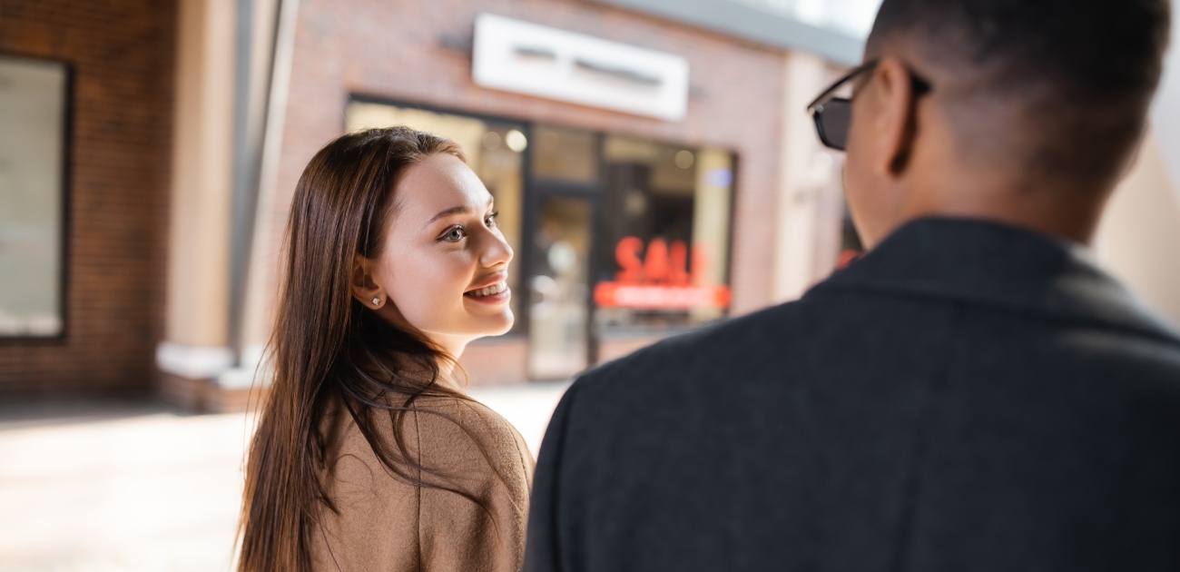 امرأة تنظر بسعادة إلى رجل يمشي بجانبها يلبس نظارات وينظر إليها أيضًا