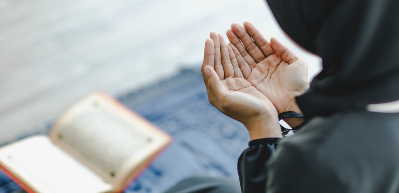 امرأة ترفع يديها للدعاء