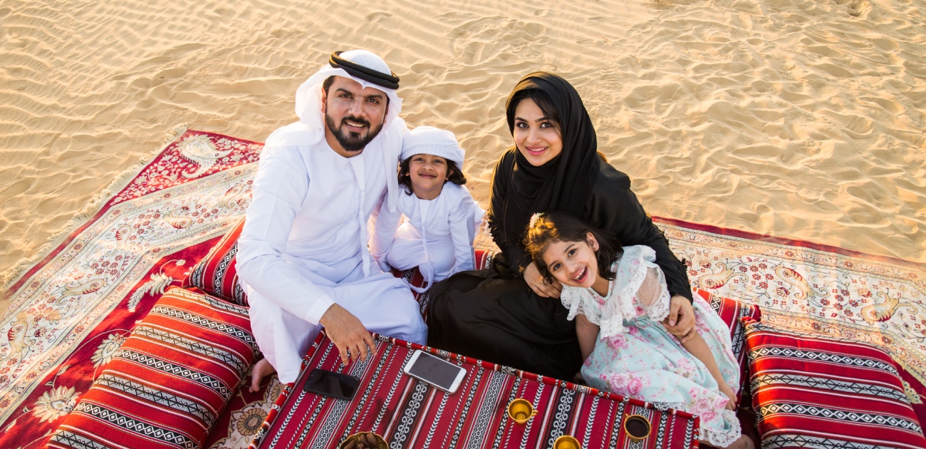أم وأب وطفلهما وطفلتهما يجلسون على الأرض في الصحراء