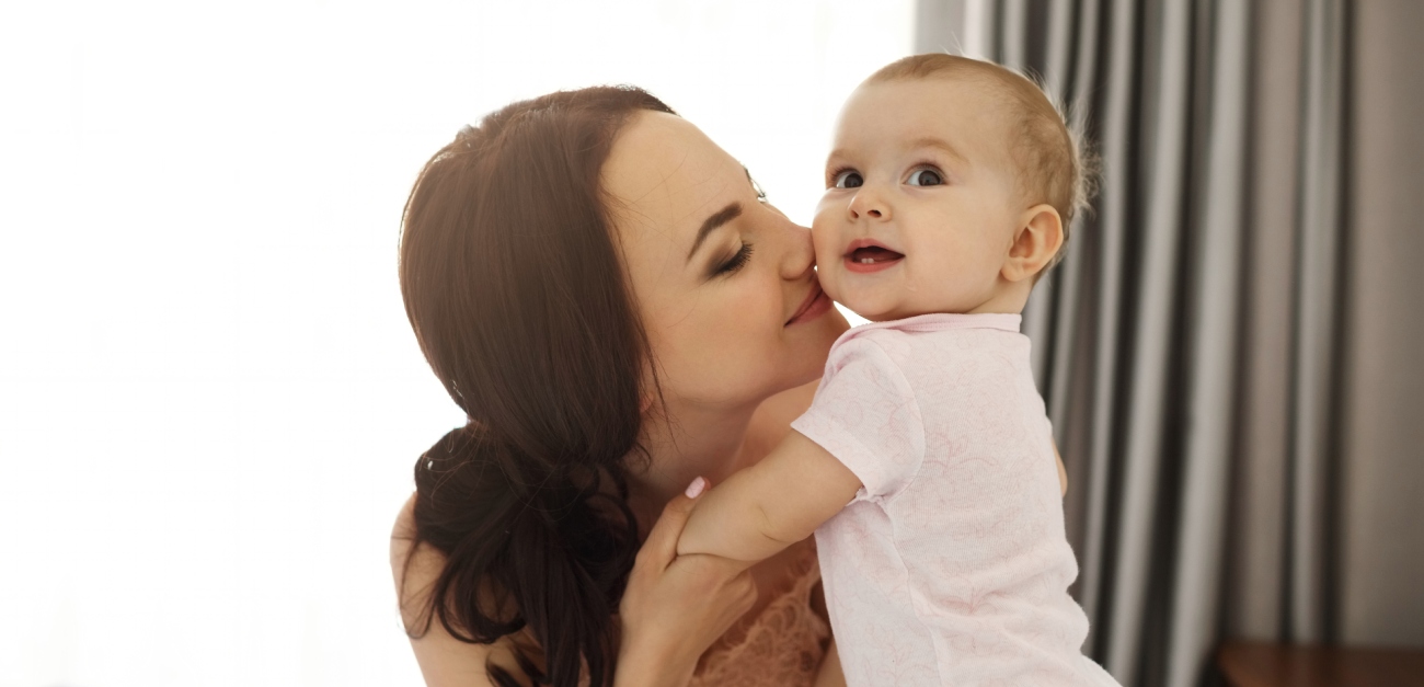 امرأة تحمل رضيعها وتقبّله