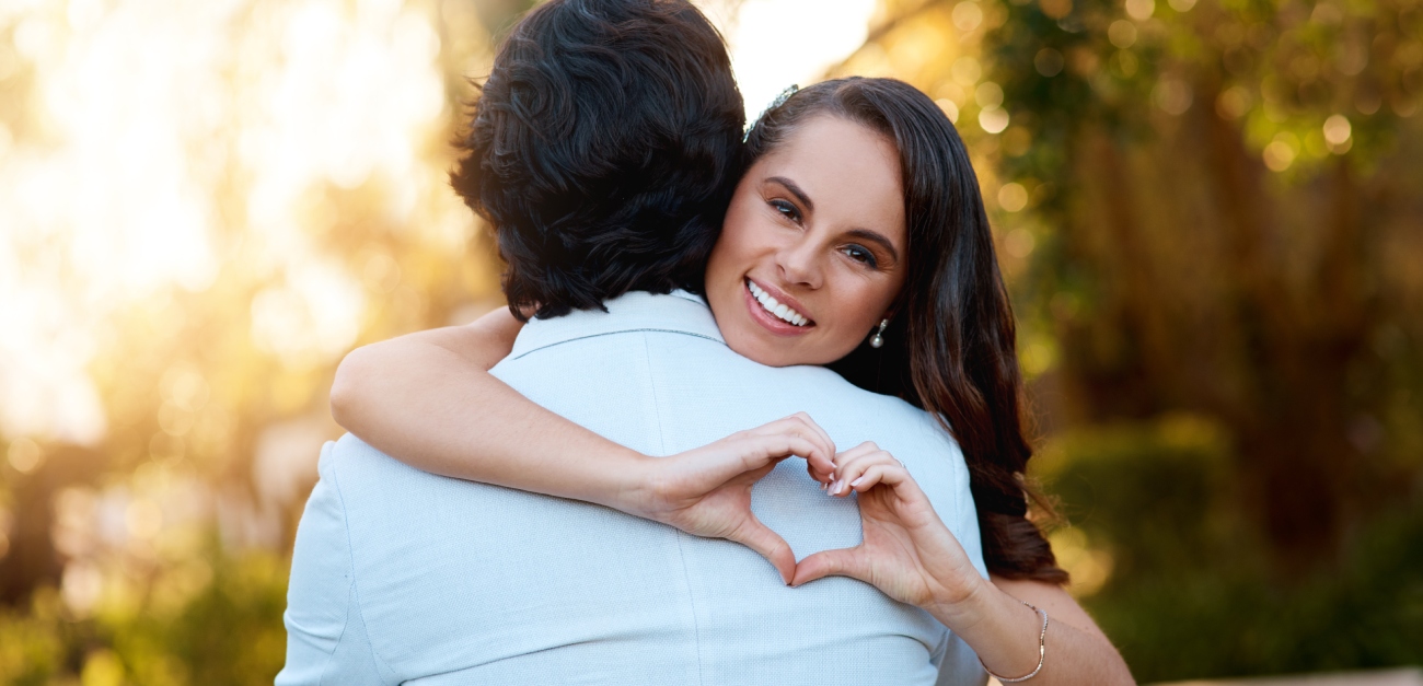 امرأة تعانق رجل وتصنع قلبًا بيديها