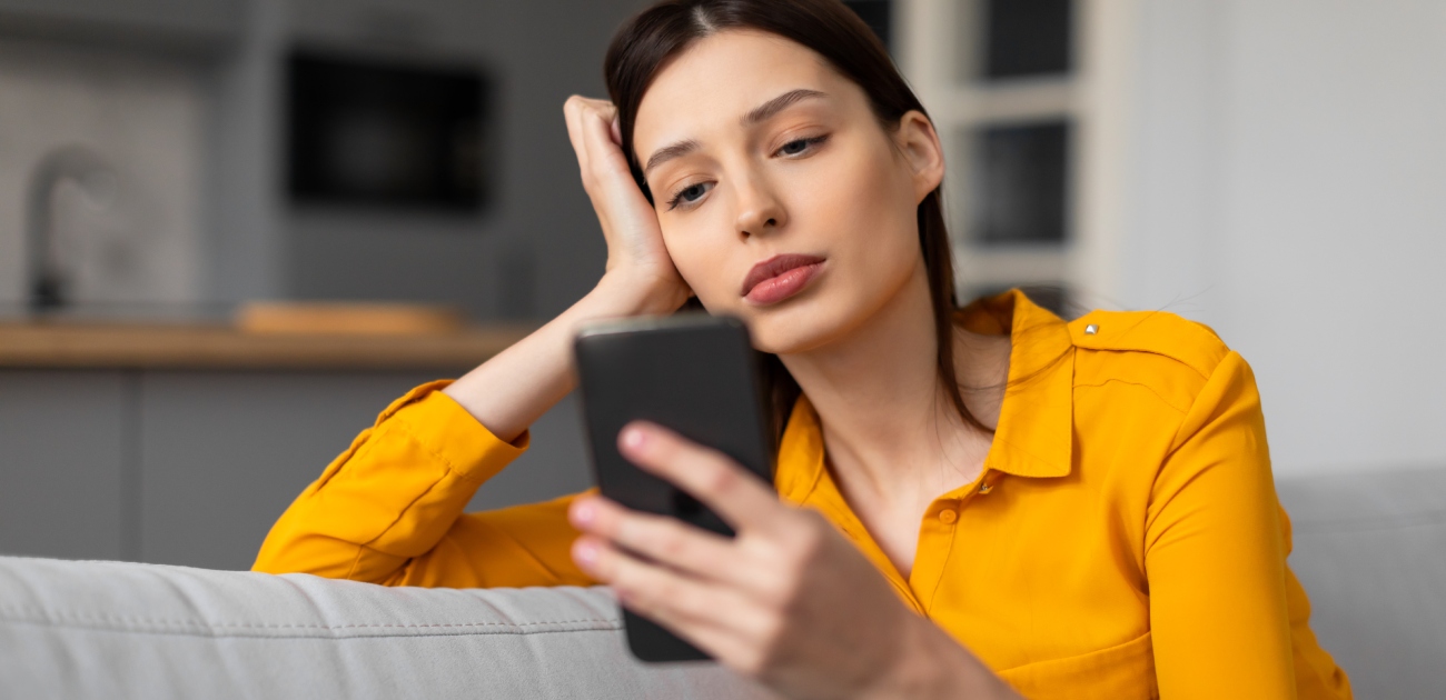 امرأة حزينة تنظر إلى هاتفها