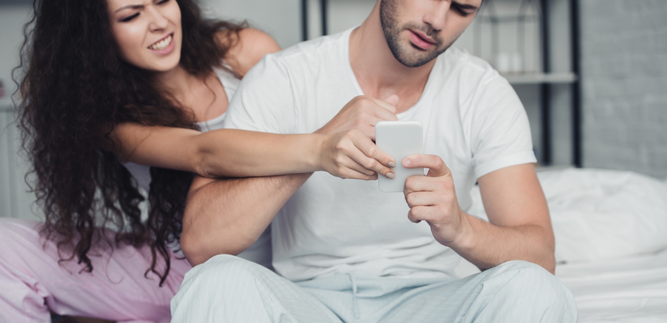 رجل يمسك هاتفه وامرأة تحاول أخذه منه