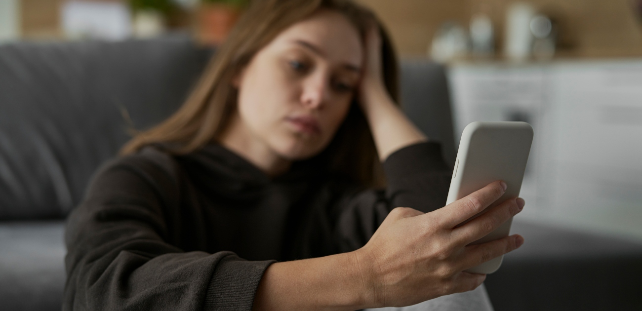 امرأة حزينة تنظر إلى هاتفها